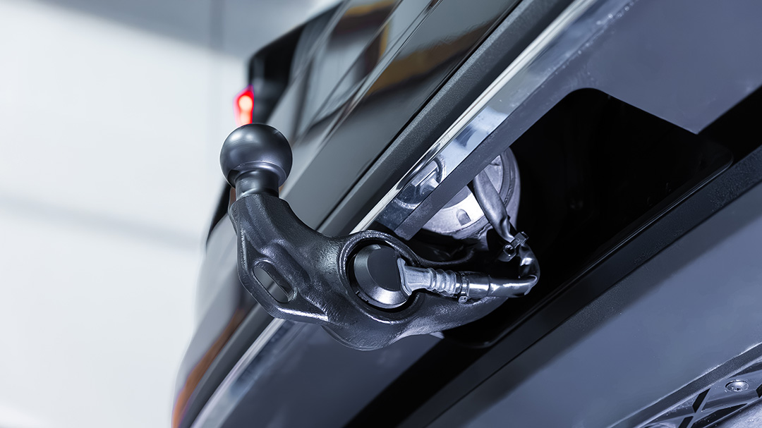 Nahaufnahme einer Anhängerkupplung an der Rückseite eines schwarzen Fahrzeugs in einer Garage oder Halle.